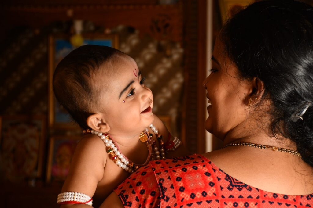 A heartwarming scene of a mother holding and smiling at her baby in a traditional setting.